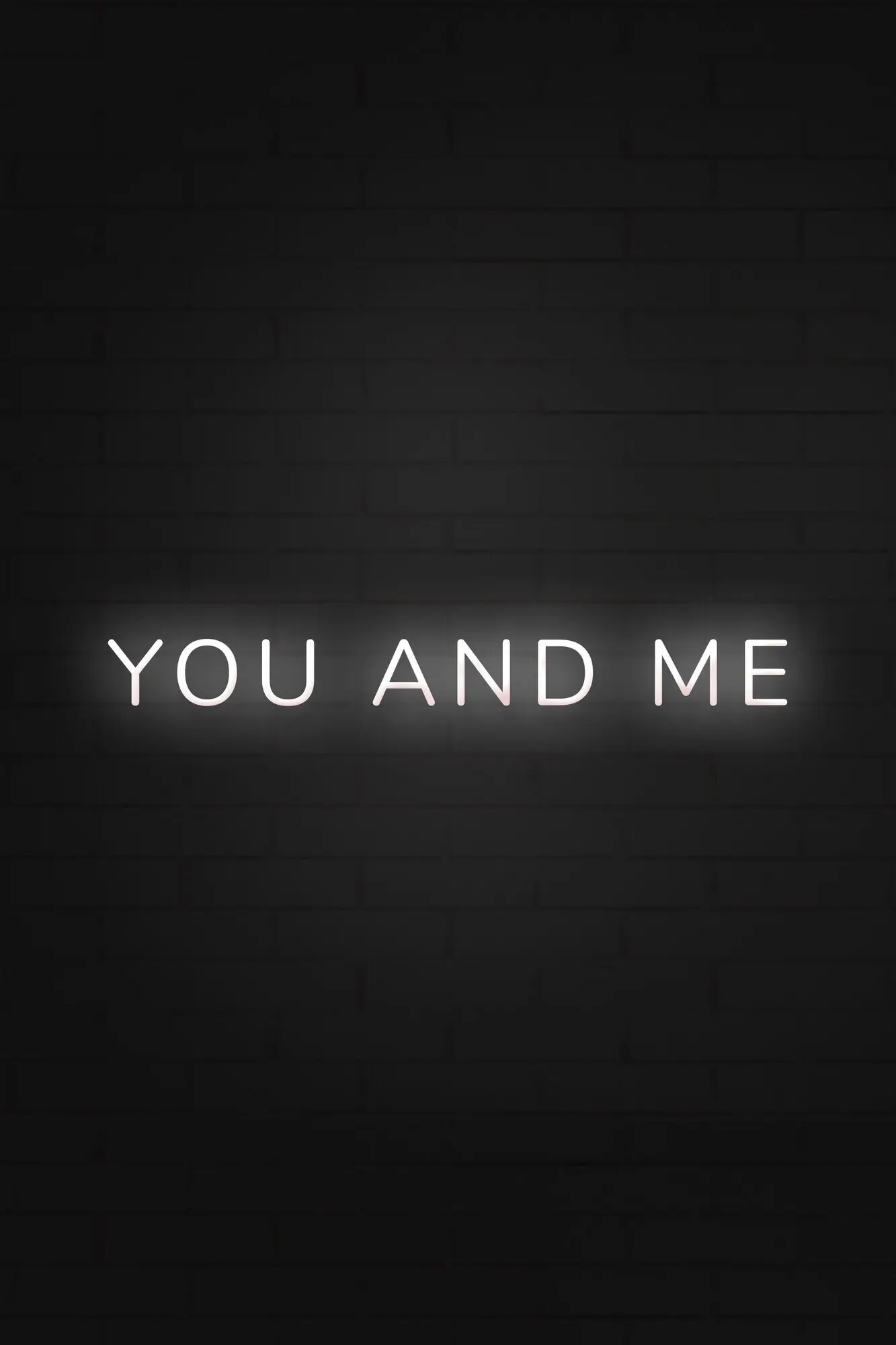 Leuchtender Neon-Schriftzug „you and me“ auf schwarzem Hintergrund.