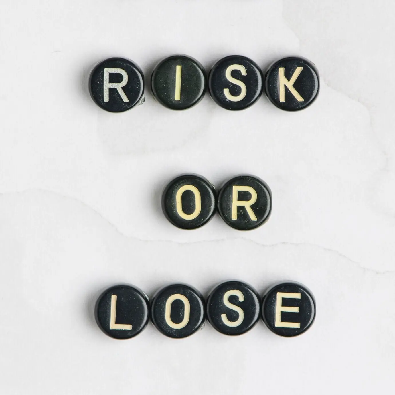 Typografie einer Botschaft aus Perlen: „RISK OR LOSE“