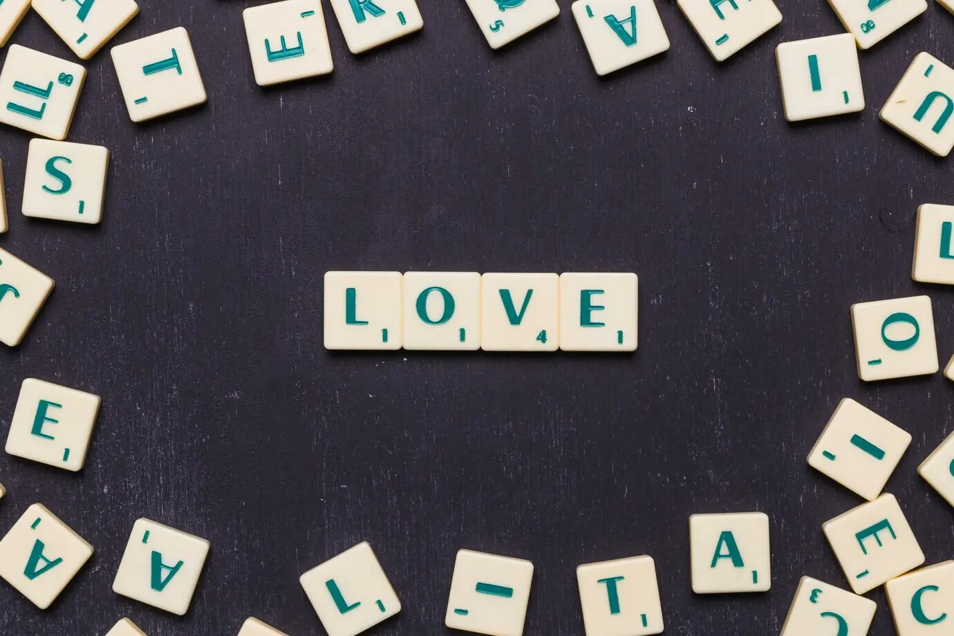 Auf schwarzem Hintergrund liegt das Wort „Love“, umgeben von Scrabble-Buchstaben.